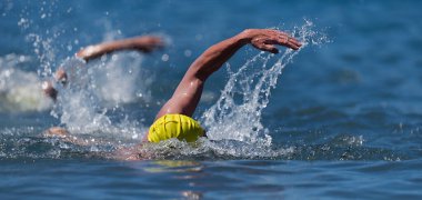 Triatlon yüzücüleri, triatlonda yarışan iki yüzücüyü suda çalkalayıp dururlar.