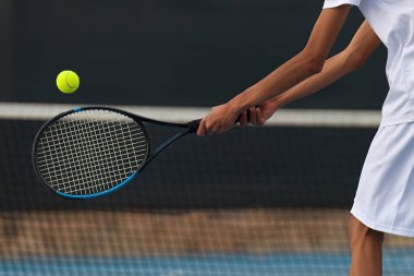 Erkek tenisçi tenis kortunda ağla ters vuruş yapıyor.
