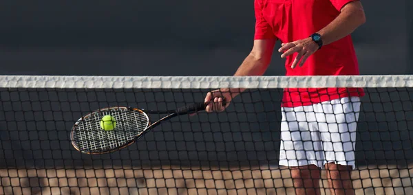 Male tennis player hitting forehand by net on the tennis court