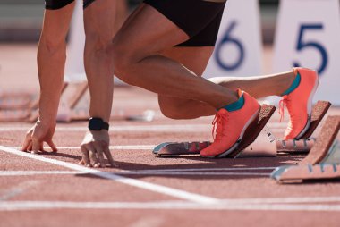 Man in a start block on an athletic track. A sprinter in a track and field race is poised at the starting line waiting for the start