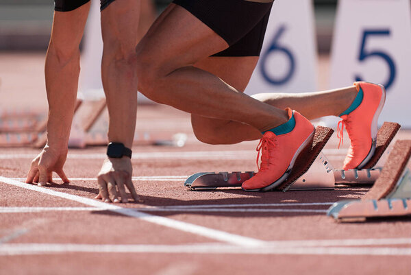 Man in a start block on an athletic track. A sprinter in a track and field race is poised at the starting line waiting for the start