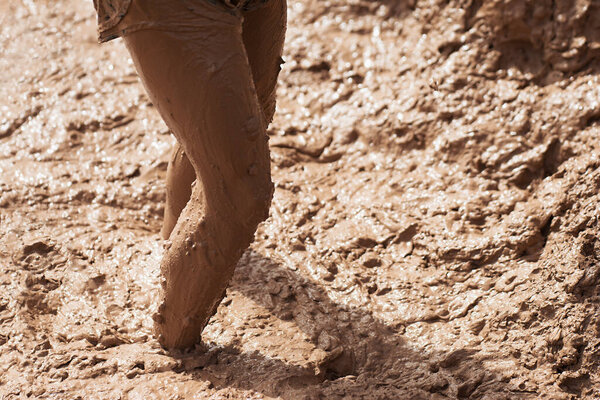 Участник грязной гонки пробирается сквозь грязные ноги