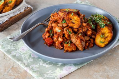 Biftek ve kızarmış muzlu fasulye güveci.