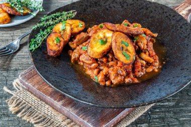 Biftek ve kızarmış muzlu fasulye güveci.