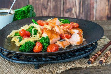 Kızarmış erikli somon balığı, domates, brokoli ve yumurtalı erişte.