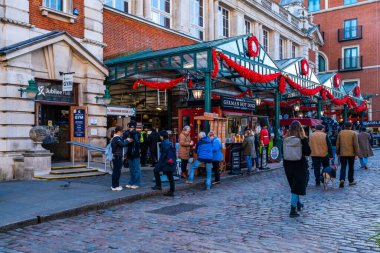LONDON, İngiltere - 11 Kasım 2021: Turistler ve Londralılar, Londra 'nın restoranları, dükkanları ve canlı eğlence merkezleriyle bilinen en popüler alışveriş ve turizm merkezlerinden biri olan Covent Garden' da günün tadını çıkarıyorlar