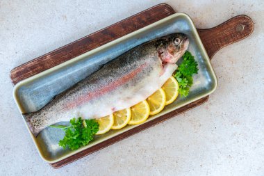 Limon dilimleriyle süslenmiş taze çiğ gökkuşağı alabalığı ve kısmen tepeden bakıldığında...