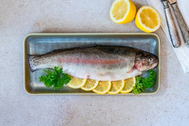Limon dilimleriyle süslenmiş taze çiğ gökkuşağı alabalığı ve kısmen tepeden bakıldığında...