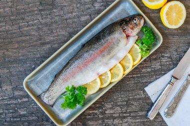 Limon dilimleriyle süslenmiş taze çiğ gökkuşağı alabalığı ve kısmen tepeden bakıldığında...