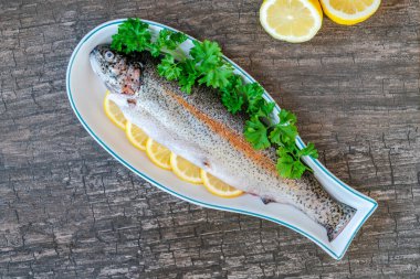 Limon dilimleriyle süslenmiş taze çiğ gökkuşağı alabalığı ve kısmen tepeden bakıldığında...