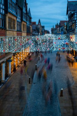 CHESTER, CheSHIRE, İngiltere - 05 Aralık 2021 Chester 'daki Eastgate Caddesi' nin alacakaranlıkta Noel ışıklarıyla süslenmiş görüntüsü.