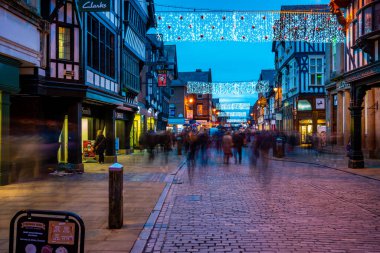 CHESTER, CheSHIRE, İngiltere - 05 Aralık 2021 Chester 'daki Eastgate Caddesi' nin alacakaranlıkta Noel ışıklarıyla süslenmiş görüntüsü.