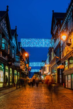 CHESTER, CheSHIRE, İngiltere - 05 Aralık 2021: Chester 'ın ünlü eski kasabası, akşam karanlığında Saflar' ı süsleyen Noel ışıklarının asıldığı sıralar