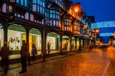 CHESTER, CheSHIRE, İngiltere - 05 Aralık 2021: Chester 'ın ünlü eski kasabası, akşam karanlığında Saflar' ı süsleyen Noel ışıklarının asıldığı sıralar