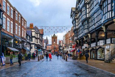 CHESTER, CheSHIRE, İngiltere - 06 Aralık 2021: Geleneksel siyah-beyaz kereste çerçeveli Tudor tarzı binalarla tarihi Chester kasabasındaki The Rows dükkanlarının görüntüsü