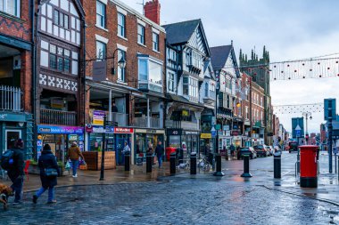 CHESTER, CheSHIRE, İngiltere - 06 Aralık 2021: Tarihi Chester kasabasındaki The Rows dükkanlarının sokak manzarası geleneksel siyah-beyaz kereste çerçeveli Tudor tarzı binalar Noel için dekore edildi