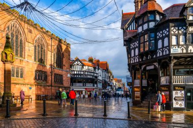 CHESTER, CheSHIRE, İngiltere - 06 Aralık 2021: Tarihi Chester kasabasındaki The Rows dükkanlarının sokak manzarası geleneksel siyah-beyaz kereste çerçeveli Tudor tarzı binalar Noel için dekore edildi