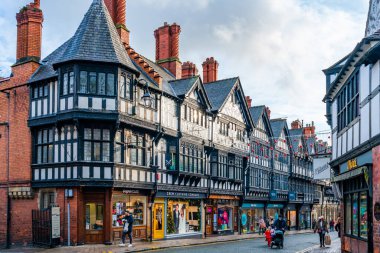 CHESTER, CheSHIRE, İngiltere - 06 Aralık 2021: Tarihi Chester kasabasındaki The Rows dükkanlarının sokak manzarası geleneksel siyah-beyaz kereste çerçeveli Tudor tarzı binalar Noel için dekore edildi
