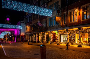 CHESTER, CheSHIRE, İngiltere - 06 Aralık 2021: Eastgate saat kulesi ve Chester 'ın ünlü eski kasabası, akşam karanlığında Saflar' ı süsleyen Noel ışıkları manzarası.