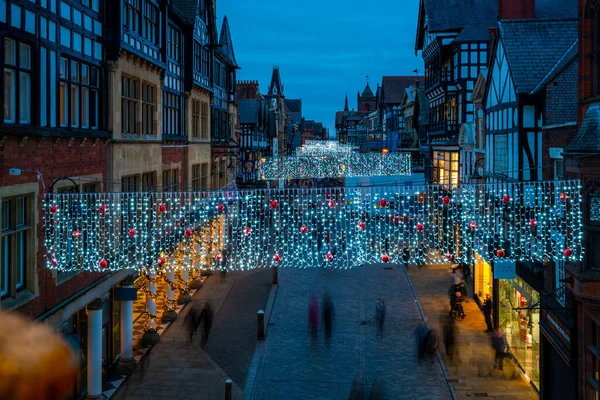 CHESTER, CheSHIRE, İngiltere - 05 Aralık 2021 Chester 'daki Eastgate Caddesi' nin alacakaranlıkta Noel ışıklarıyla süslenmiş görüntüsü.