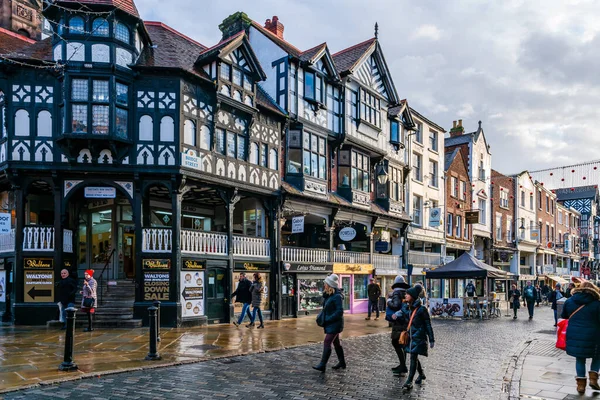 CHESTER, CheSHIRE, İngiltere - 06 Aralık 2021: Tarihi Chester kasabasındaki The Rows dükkanlarının sokak manzarası geleneksel siyah-beyaz kereste çerçeveli Tudor tarzı binalar Noel için dekore edildi