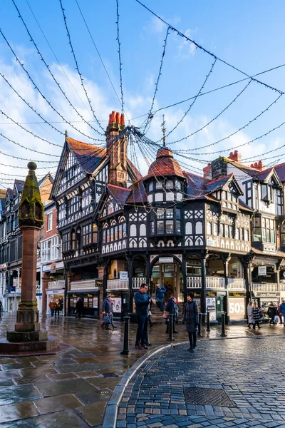 CHESTER, CheSHIRE, İngiltere - 06 Aralık 2021: Tarihi Chester kasabasındaki The Rows dükkanlarının sokak manzarası geleneksel siyah-beyaz kereste çerçeveli Tudor tarzı binalar Noel için dekore edildi