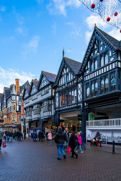 CHESTER, CheSHIRE, İngiltere - 06 Aralık 2021: Tarihi Chester kasabasındaki The Rows dükkanlarının sokak manzarası geleneksel siyah-beyaz kereste çerçeveli Tudor tarzı binalar Noel için dekore edildi