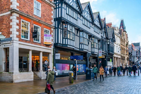 CHESTER, CheSHIRE, İngiltere - 06 Aralık 2021: Tarihi Chester kasabasındaki The Rows dükkanlarının sokak manzarası geleneksel siyah-beyaz kereste çerçeveli Tudor tarzı binalar Noel için dekore edildi