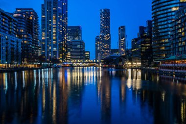 LONDON, İngiltere - 09 Ocak 2022: Londra 'nın finans merkezi olan Canary Wharf' taki Millwall Inner Rıhtımı boyunca modern gökdelenlerin akşam manzarası.