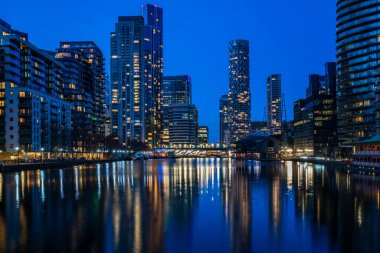 LONDON, İngiltere - 09 Ocak 2022: Londra 'nın finans merkezi olan Canary Wharf' taki Millwall Inner Rıhtımı boyunca modern gökdelenlerin akşam manzarası.