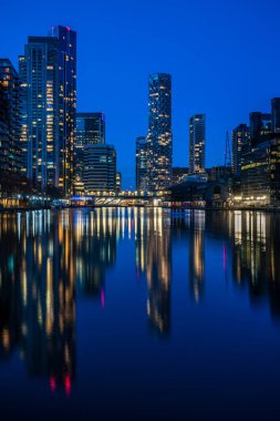 LONDON, İngiltere - 09 Ocak 2022: Londra 'nın finans merkezi olan Canary Wharf' taki Millwall Inner Rıhtımı boyunca modern gökdelenlerin akşam manzarası.