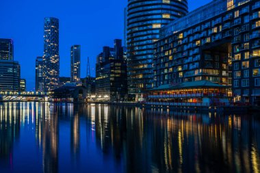 LONDON, İngiltere - 09 Ocak 2022: Londra 'nın finans merkezi olan Canary Wharf' taki Millwall Inner Rıhtımı boyunca modern gökdelenlerin akşam manzarası.