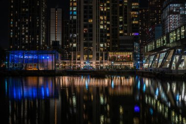 LONDON, İngiltere - 09 Ocak 2022: Londra 'nın finans merkezi olan Canary Wharf' taki Millwall İç Rıhtımı boyunca modern gökdelenlerin gece görüşü.