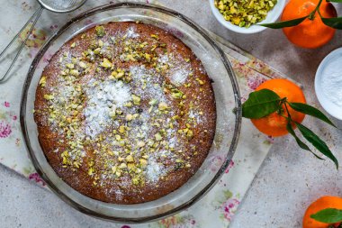 Fıstıklı ve portakallı pasta üzerine şeker ve ezilmiş fıstık serpiştirilmiş.