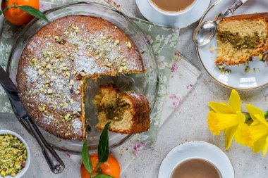 Fıstıklı ve portakallı pasta üzerine şeker ve ezilmiş fıstık serpiştirilmiş.