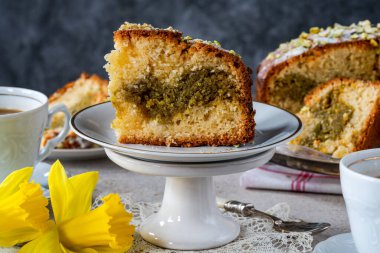 Fıstıklı ve portakallı pasta üzerine şeker ve ezilmiş fıstık serpiştirilmiş.