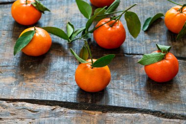 Ahşap masa üzerinde yeşil yapraklı portakallar.