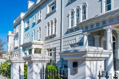 LONDON, İngiltere - 19 Mart 2022: Notting Hill 'deki Ladbroke Grove yerleşim sokağındaki renkli teraslı evler, işlek pazarı ve yıllık Notting Hill Karnavalı ile tanınan zengin bir bölge