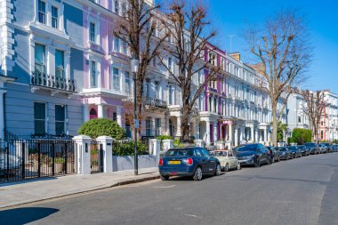 LONDON, İngiltere - 19 Mart 2022: Notting Hill 'deki Ladbroke Grove yerleşim sokağındaki renkli teraslı evler, işlek pazarı ve yıllık Notting Hill Karnavalı ile tanınan zengin bir bölge