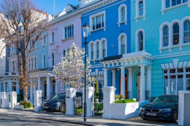 LONDON, İngiltere - 19 Mart 2022: Notting Hill 'deki Ladbroke Grove yerleşim sokağındaki renkli teraslı evler, işlek pazarı ve yıllık Notting Hill Karnavalı ile tanınan zengin bir bölge