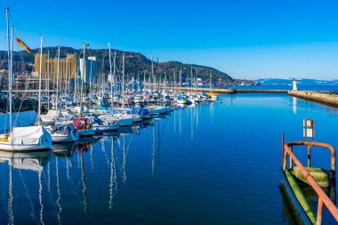 TRONDHEIM, NORway - 11 Mart 2022: arka planda Skansen deniz feneri ile demirli yelkenli yelkenli marina görüntüsü.
