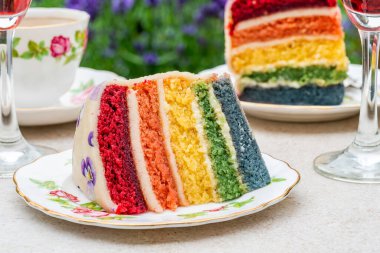 Bahçe masasında çoklu katmanlı gökkuşağı pastası. Açık hava yemeği.