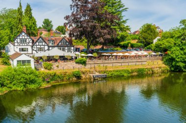 SHREWSBURY, UK - JULY 11, 2022: The Boathouse pub in Shrewsbury is a mock Tudor pub with wooden deck on River Severn's edge, overlooking Shrewsbury's idyllic Quarry park