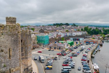 CAERNARFON, WALES - 08 Temmuz 2022: Ortaçağ Kalesi duvarlarından Caernarfon manzarası. Caernarfon Galler 'in Gwynedd şehrinde bulunan bir kraliyet şehridir.