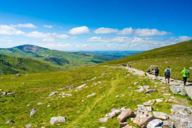 SNOWDON, WALES - JULY 09, 2022: Hikers walk dawn from Mount Snowdon after reaching the summit. Snowdon is the highest mountain in Wales, at an elevation of 1,085 metres above sea level
