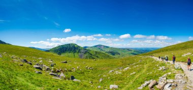 SNOWDON, WALES - JULY 09, 2022: Hikers walk down from Mount Snowdon after reaching the summit. Snowdon is the highest mountain in Wales, at an elevation of 1,085 metres above sea level