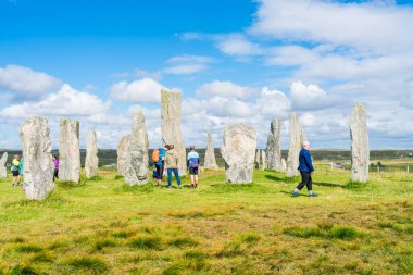 CALLANISH, ISLE OF LEWIS, SCOTLAND - AUGUST 03, 2022: Tourists visit Callanish standing stones site on the Isle of Lewis. The stones were erected in the late Neolithic era.