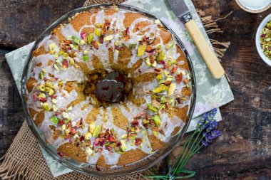 Vanilya kremalı, ezilmiş şam fıstığı ve kurutulmuş gül yapraklarıyla süslenmiş İran aşk pastası.