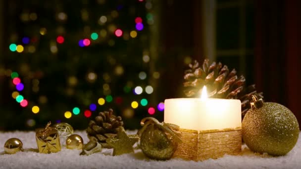 Adventní svíčka se zlatými ozdobami na bílém sněhu. — Stock video