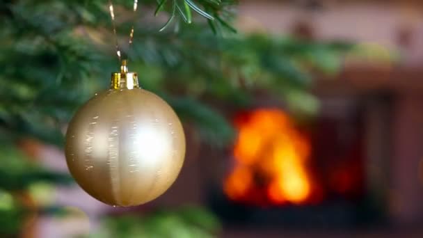 Gouden kerstbal tegen een stenen haard. Bokeh vakantie lichte achtergrond. — Stockvideo